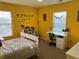 Bedroom with yellow walls, carpet, and a study desk at 10636 Racine Cir, Commerce City, CO 80022