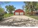 Red garage with two doors and large driveway, framed by mature trees and lawn at 14505 W 52Nd Ave, Arvada, CO 80002