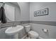 Stylish half bathroom featuring a pedestal sink, decorative wall stripes, and a modern framed floral art at 15201 Yellowthroat St, Parker, CO 80134