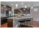 Modern kitchen with dark wood cabinets, stainless steel appliances, large granite island with seating, and hardwood floors at 15201 Yellowthroat St, Parker, CO 80134