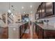 Open kitchen featuring dark wood cabinetry, stainless appliances, granite counters, and hardwood floors leading to staircase at 15201 Yellowthroat St, Parker, CO 80134