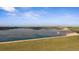 The aerial view shows the lake with a dam surrounded by green fields under a blue sky at 15201 Yellowthroat St, Parker, CO 80134