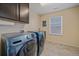 Laundry room equipped with modern washer and dryer, ample cabinet space, and tiled floors at 15201 Yellowthroat St, Parker, CO 80134