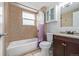 Bathroom features a tub-shower, single vanity, and neutral tile at 5542 Sable St, Denver, CO 80239