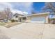 View of the well-maintained brick home, landscaped front yard, long driveway, and an attached two-car garage at 5542 Sable St, Denver, CO 80239