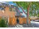 Exterior view of a property with a wooden fence, a large tree, and designated parking spaces at 7995 E Mississippi Ave # F23, Denver, CO 80247