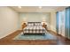 Bright bedroom featuring hardwood floors, a cozy bed with a patterned quilt, and bedside tables with lamps and great area rug at 4553 Red Deer Trl, Broomfield, CO 80020