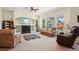 Bright living room featuring a ceiling fan, fireplace, large windows and comfortable leather furniture at 4553 Red Deer Trl, Broomfield, CO 80020