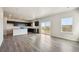 Bright open living space with wood-style flooring, large windows, and a kitchen in the background at 19059 E 94Th Pl, Commerce City, CO 80022