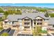 Inviting condo building featuring a gray roof, beige siding, balconies, and well-kept landscaping at 7433 S Quail Cir # 1924, Littleton, CO 80127