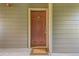 Brown wooden front door with gold hardware, a welcome mat, and wood siding at 7433 S Quail Cir # 1924, Littleton, CO 80127