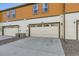 Contemporary townhome features a two-car garage and clean architectural lines with a paved driveway and xeriscaping at 21613 E 59Th Pl, Aurora, CO 80019