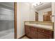 Bathroom with wood cabinets, a tile countertop, a large mirror, and a glass-enclosed shower at 26426 E Peakview Dr, Aurora, CO 80016