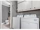 Laundry room with stacked washer/dryer, white cabinets, and a view into the nearby bathroom at 1745 S Kline Way, Lakewood, CO 80232