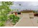 Single-story home with a red front door, solar panels, one car garage, and beautiful landscaping at 9743 W 67Th Pl, Arvada, CO 80004
