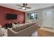 Living room with a red accent wall, hardwood floors, ceiling fan, and a large TV at 9743 W 67Th Pl, Arvada, CO 80004