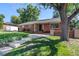 Charming brick home featuring a well-manicured lawn, stone walkway, and mature trees at 2724 S Ames Way, Denver, CO 80227