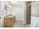 Updated bathroom featuring double vanity, shower with tile surround, and modern fixtures at 7238 W Cedar Cir, Lakewood, CO 80226