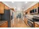 Open concept kitchen with stainless steel appliances, wood cabinets, and hardwood floors at 7238 W Cedar Cir, Lakewood, CO 80226