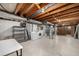 Unfinished basement with exposed wood ceiling, shelving, and laundry area at 7238 W Cedar Cir, Lakewood, CO 80226