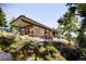 Modern glass house nestled into a hillside with outdoor patio furniture and surrounded by lush greenery at 53 Canyon Pines Dr, Golden, CO 80403