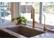 Close up of a modern kitchen sink with stone countertop, and brass fixtures at 7600 S Ulster Ct, Centennial, CO 80112