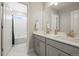 Bright bathroom featuring double sink vanity with white countertops, large mirror, and view into the shower/tub at 1624 Pinion Wing Cir, Castle Rock, CO 80108
