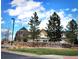 Inviting entrance to The Lakehouse at Southshore, framed by mature trees and manicured landscaping, under a vibrant blue sky at 26642 E Peakview Pl, Aurora, CO 80016