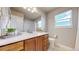 Bright bathroom featuring dual sinks, a large mirror, and a window above the toilet at 12701 Strawberry Cir, Longmont, CO 80503