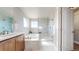 Well-lit bathroom featuring a soaking tub with a glass shower, a large vanity, and tile flooring at 12701 Strawberry Cir, Longmont, CO 80503