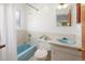 Functional bathroom with a tiled blue bathtub, toilet, and a matching sink, offering essential amenities at 2900 S Golden Way, Denver, CO 80227