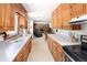 Galley kitchen with wood cabinetry, white countertops, and a view into the living area with a stone fireplace at 2900 S Golden Way, Denver, CO 80227