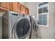 Modern laundry room with front load washer and dryer and wooden cabinets at 11788 Mill Valley St, Parker, CO 80138