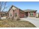 Charming exterior view of a home featuring a two-car garage, stone accents, and a well-manicured lawn at 4533 Angelina Cir, Longmont, CO 80503
