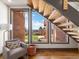 Inviting living room with a cozy chair, hardwood floors, and a view to the backyard and staircase at 43 Falcon Hills Dr, Highlands Ranch, CO 80126