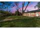 Backyard at dusk featuring a large, green lawn, and a brick house with a covered patio at 1269 N Revere St, Aurora, CO 80011