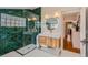 Stylish bathroom featuring green tiled shower, modern vanity, round mirror, and wood floors at 3259 Lowell Blvd, Denver, CO 80211