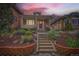 Charming brick home featuring a cozy front porch, brick garden bed, and inviting red front door at sunset at 3259 Lowell Blvd, Denver, CO 80211