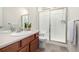 Bright bathroom featuring a glass-enclosed shower, wood vanity, and neutral tile flooring at 9723 Bennett Peak St, Littleton, CO 80125