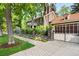 Elegant brick home featuring a private driveway, lush landscaping, a manicured lawn, and an attached garage at 3309 E 7Th Ave Pkwy, Denver, CO 80206