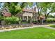 Stately brick home with a classic white balcony, surrounded by mature trees and meticulously manicured landscaping at 3309 E 7Th Ave Pkwy, Denver, CO 80206