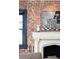 Close up shot of a fireplace mantel with a picture hanging above and a brick accent wall at 3309 E 7Th Ave Pkwy, Denver, CO 80206