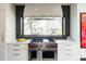 Gourmet kitchen featuring stainless steel appliances, white cabinetry, and a view of the backyard at 3309 E 7Th Ave Pkwy, Denver, CO 80206