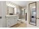 Bathroom with white vanity, tub with sliding door, large mirror, and a view into another room at 504 E Otero Ct, Littleton, CO 80122