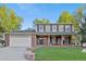 Beautiful two-story home with well-kept lawn, covered entry, brick accents, and an attached garage at 504 E Otero Ct, Littleton, CO 80122
