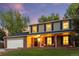 Inviting two-story home featuring a cozy covered front porch, a well-manicured lawn, and warm lighting at 504 E Otero Ct, Littleton, CO 80122