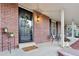 Charming front porch with a seating area, brick detail, stylish lighting, and a welcoming entrance at 504 E Otero Ct, Littleton, CO 80122