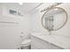 A stylish bathroom featuring a round mirror, white vanity, toilet, and shower at 3285 N Monaco Pkwy, Denver, CO 80207