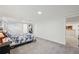 Spacious bedroom with carpet, neutral walls, a bed with floral bedding, and a view to a bathroom at 3285 N Monaco Pkwy, Denver, CO 80207