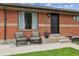 Inviting front porch with seating, flower pot, and a well-maintained lawn at 7833 Raritan St, Denver, CO 80221